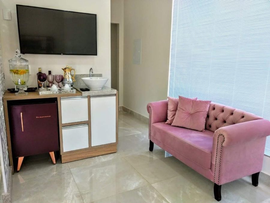 Espaço de espera com sofá rosa, café e água saborizada